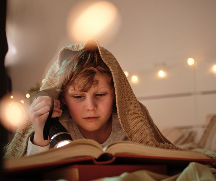 chambrekids-enfant-qui-lit-avec-une-lumiere-article-routine-sommeil-saine